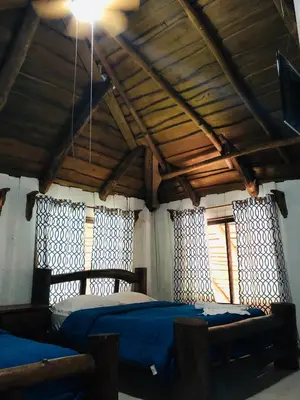 a bedroom with a bed with blue sheets and windows at Hotel Samsara in Uvita