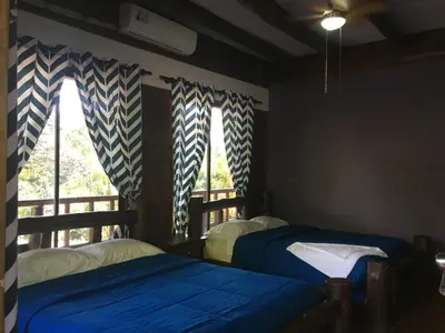 two beds in a room with two windows at Hotel Samsara in Uvita