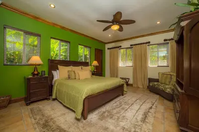a bedroom with green walls and a bed and a fan at Casa Oasis 5 bdrs private pool in Los Suenos in Herradura