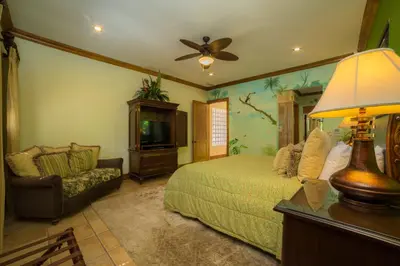 a bedroom with a bed and a tv and a couch at Casa Oasis 5 bdrs private pool in Los Suenos in Herradura