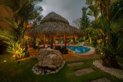 a resort with a large straw hut and a swimming pool at Casa Oasis 5 bdrs private pool in Los Suenos in Herradura