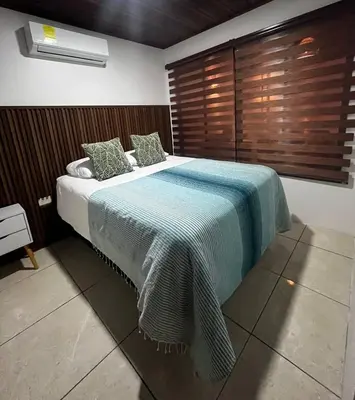 a bedroom with a large bed with a blue blanket at Mevak Apartments Suites in Fortuna