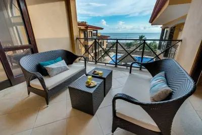 a balcony with two chairs and a couch and a table at Beautiful and Enchanting Beach Vacation in Jacó