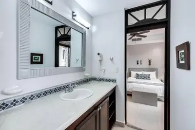 a bathroom with a sink and a mirror and a bed at Beautiful and Enchanting Beach Vacation in Jacó