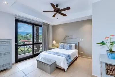 a bedroom with a bed and a ceiling fan at Beautiful and Enchanting Beach Vacation in Jacó
