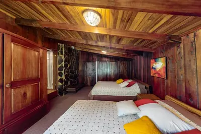a room with two beds in a wooden cabin at Hacienda Milinda in Birrí