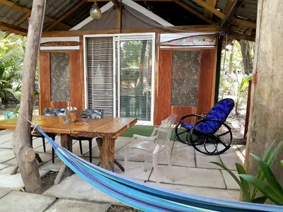 a hammock and a table and chairs on a porch at Fully Furnished FAMILY JUNGLE TENT, Latino Glamping Paquera in Paquera