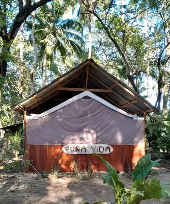 a small shed with a sign on it in front of trees at Fully Furnished FAMILY JUNGLE TENT, Latino Glamping Paquera in Paquera