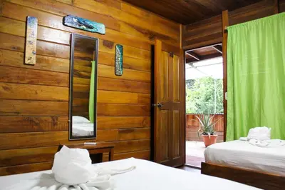 a bedroom with wooden walls and two beds and a mirror at Hotel La Cascada in Puntarenas