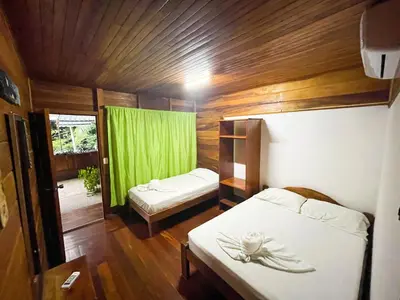a small room with two beds and a green curtain at Hotel La Cascada in Puntarenas