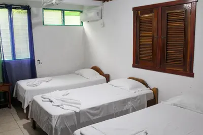a room with three beds and a window at Hotel La Cascada in Puntarenas