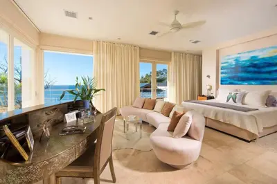 a bedroom with a bed and a couch and a table at Exquisite Hilltop Villa with Luxurious Modern Design, Sweeping Ocean Views & Sparkling Infinity Pool in Playa Flamingo