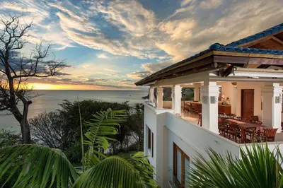 a house with a view of the ocean at sunset at Exquisite Hilltop Villa with Luxurious Modern Design, Sweeping Ocean Views & Sparkling Infinity Pool in Playa Flamingo