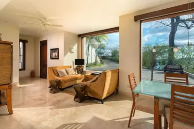 a living room with chairs and a table and a large window at Exquisite Hilltop Villa with Luxurious Modern Design, Sweeping Ocean Views & Sparkling Infinity Pool in Playa Flamingo