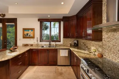 a large kitchen with wooden cabinets and a sink at Exquisite Hilltop Villa with Luxurious Modern Design, Sweeping Ocean Views & Sparkling Infinity Pool in Playa Flamingo