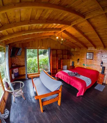 a bedroom with a bed and a chair in a cabin at Paraíso Quetzal Lodge in Tres de Junio