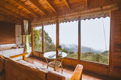 a living room with a table and large windows at Paraíso Quetzal Lodge in Tres de Junio