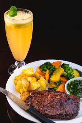 a plate of food with meat and vegetables and a drink at Paraíso Quetzal Lodge in Tres de Junio