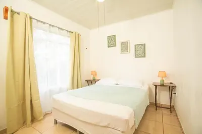 a white bedroom with a bed and a window at Cozy coworking Casa Alma near Lake Arenal, 2 bedroom 1 office, fiber optic, pet friendly in Nuevo Arenal