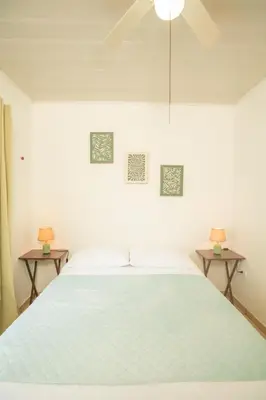 a white bedroom with a large bed with two tables at Cozy coworking Casa Alma near Lake Arenal, 2 bedroom 1 office, fiber optic, pet friendly in Nuevo Arenal