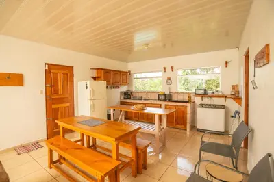 a kitchen with a table and a refrigerator at Cozy coworking Casa Alma near Lake Arenal, 2 bedroom 1 office, fiber optic, pet friendly in Nuevo Arenal