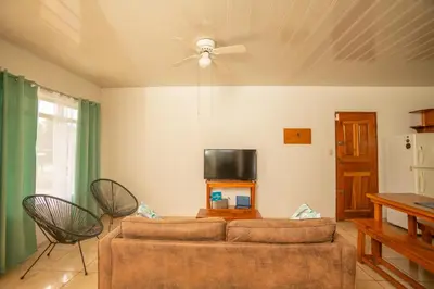 a living room with a couch and a tv at Cozy coworking Casa Alma near Lake Arenal, 2 bedroom 1 office, fiber optic, pet friendly in Nuevo Arenal