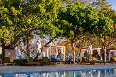 a group of chairs and umbrellas next to a pool at Terrace 2BR Condo - Bougainvillea - Reserva Conchal Golf Resort in Playa Conchal