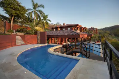 a house with a swimming pool in front of a house at Terrace 2BR Condo - Bougainvillea - Reserva Conchal Golf Resort in Playa Conchal