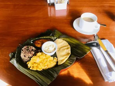 a plate of breakfast foods on a table with a cup of coffee at Nandel Beach Resort in La Cruz