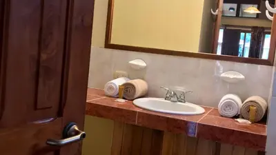 a bathroom with a sink and a mirror and towels at Nandel Beach Resort in La Cruz