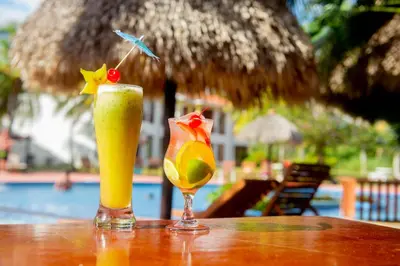 two drinks sitting on a table next to a pool at Nandel Beach Resort in La Cruz