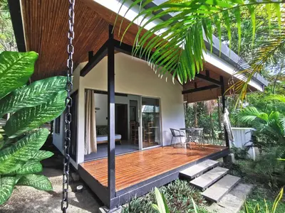 a house with a wooden porch with a swing at Armadillo Bungalows, walk to the Beach - Santa Teresa in Santa Teresa Beach