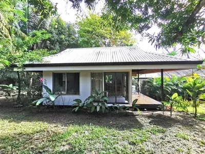 a small white house with a porch and trees at Armadillo Bungalows, walk to the Beach - Santa Teresa in Santa Teresa Beach