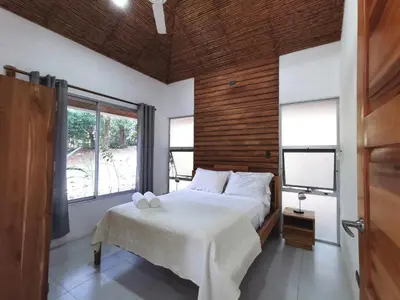a bedroom with a bed and a large window at Armadillo Bungalows, walk to the Beach - Santa Teresa in Santa Teresa Beach