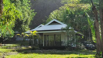 a small white house in the middle of trees at Armadillo Bungalows, walk to the Beach - Santa Teresa in Santa Teresa Beach