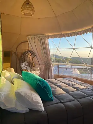 a bedroom with a bed with pillows and a window at Kintiri Glamping in Nicoya