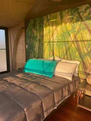 a bed in a tent with a painting on the wall at Kintiri Glamping in Nicoya