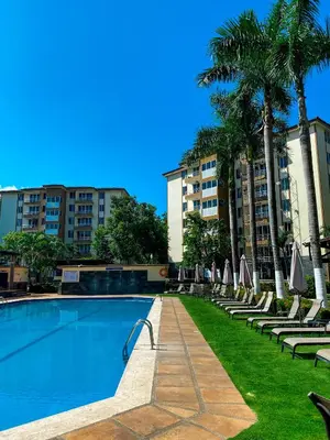 a swimming pool with chairs and palm trees and buildings at Costa Linda 6-08 in Jacó
