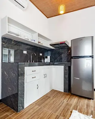 a kitchen with white cabinets and a stainless steel refrigerator at BUDDA HOME in Tortuguero