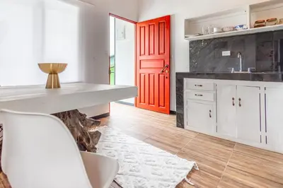 a kitchen with white cabinets and a red door at BUDDA HOME in Tortuguero