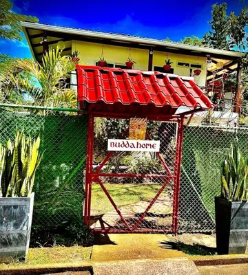 a fence with a red roof in front of a house at BUDDA HOME in Tortuguero