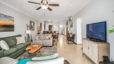 a living room with a couch and a tv at Elegant Oceanview Condo with Spacious Open-Concept Floor Plan and Inviting Beach Design in Playa Flamingo