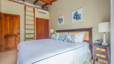 a bedroom with a white bed and a wooden door at Chic Condo with a Stylish Coastal Design in an Exclusive Condo Community with Direct Beach Access in Playa Flamingo