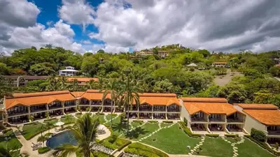 an aerial view of a resort with a pool and trees at Chic Condo with a Stylish Coastal Design in an Exclusive Condo Community with Direct Beach Access in Playa Flamingo
