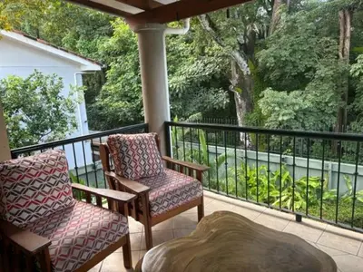 a porch with two chairs and a table on a balcony at Jazmin Del Sol steps away from Playa Potrero !! in Potrero