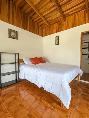 a bedroom with a white bed in a room with wooden ceilings at El Nido Lodge in Monteverde Costa Rica