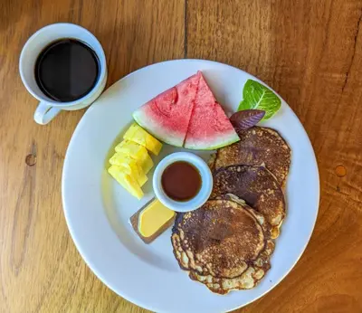 a plate with pancakes and fruit and a cup of coffee at El Nido Lodge in Monteverde Costa Rica