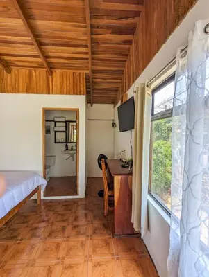 a room with a bed and a desk and a window at El Nido Lodge in Monteverde Costa Rica
