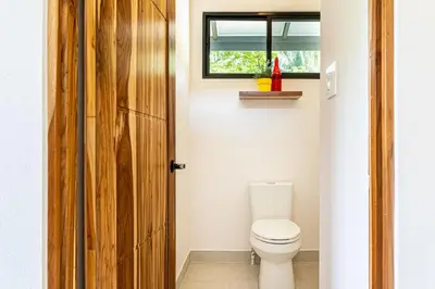 a bathroom with a toilet and a window at The Sutton - Boutique Jungle Experience - Walk to Envision Festival in Uvita
