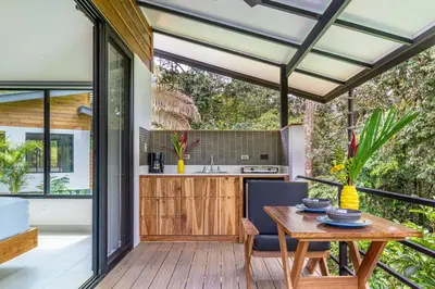 an open kitchen and dining room with a wooden table at The Sutton - Boutique Jungle Experience - Walk to Envision Festival in Uvita